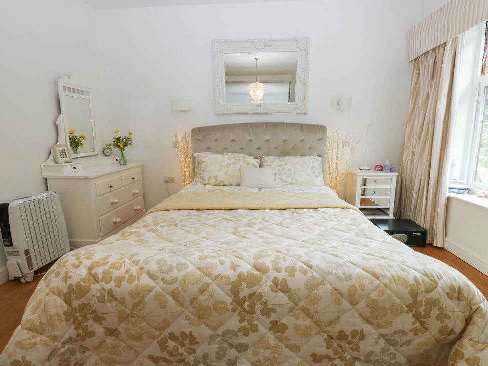 A bedroom with a large bed and dresser at St Mary's House in Oldham