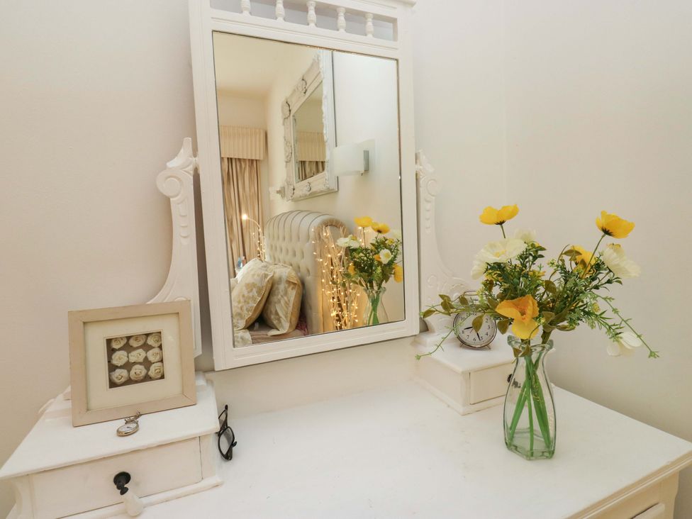 A dressing table with a mirror and flowers at St Mary's House in Oldham