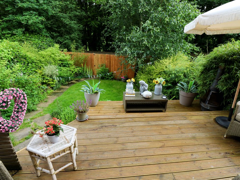 A garden with decking, table and potted plants at St Mary's House, Oldham