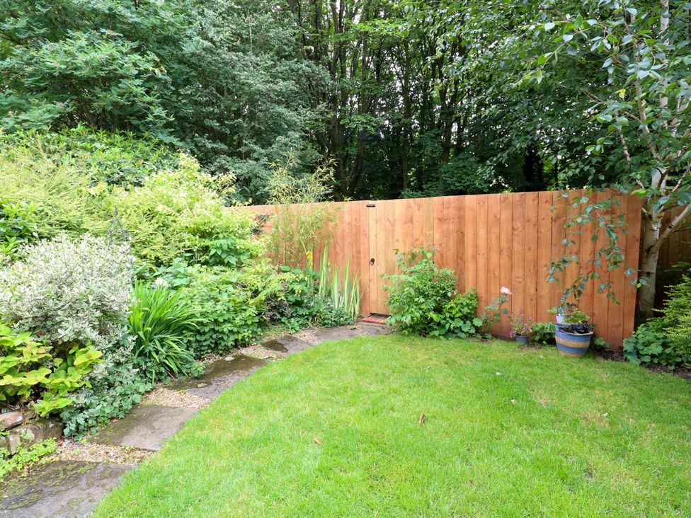 A garden with grass and plants beside a wooden fence at St Mary's House in Oldham