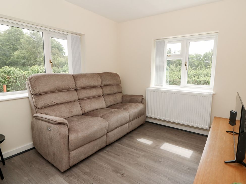 A living room with a sofa and television at Glandwr House in Llandrindod Wells