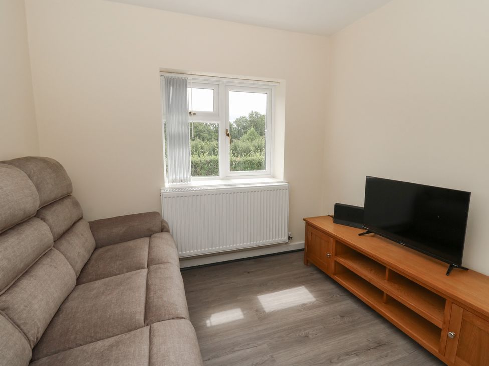 A living room with a sofa and a television at Glandwr House in Llandrindod Wells