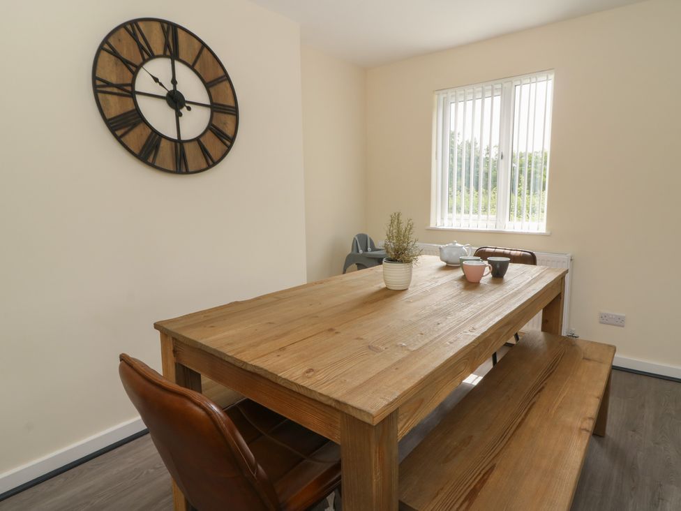 A dining room with a wooden table and clock at Glandwr House Llandrindod Wells