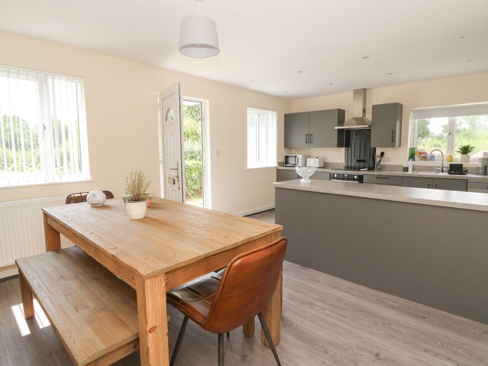 A kitchen with a wooden table and chairs at Glandwr House in Llandrindod Wells