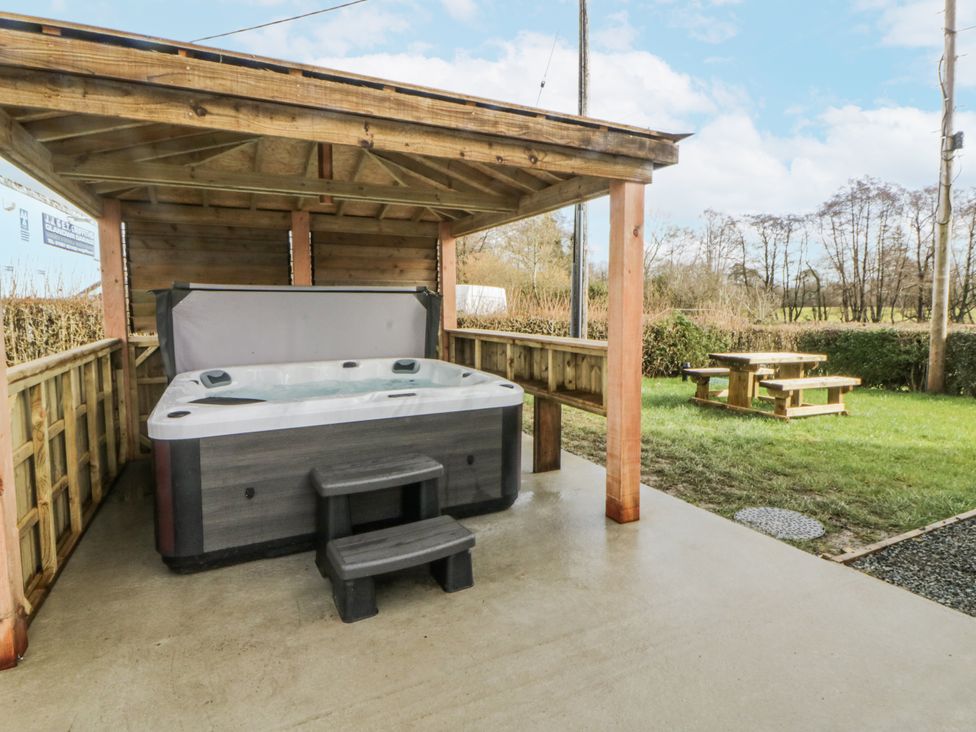 A hot tub under a wooden shelter in an outdoor area at Glandwr House Crossgates near Llandrindod Wells