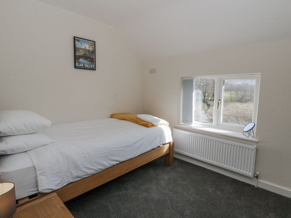 A bedroom with a bed and window at Glandwr House in Crossgates near Llandrindod Wells