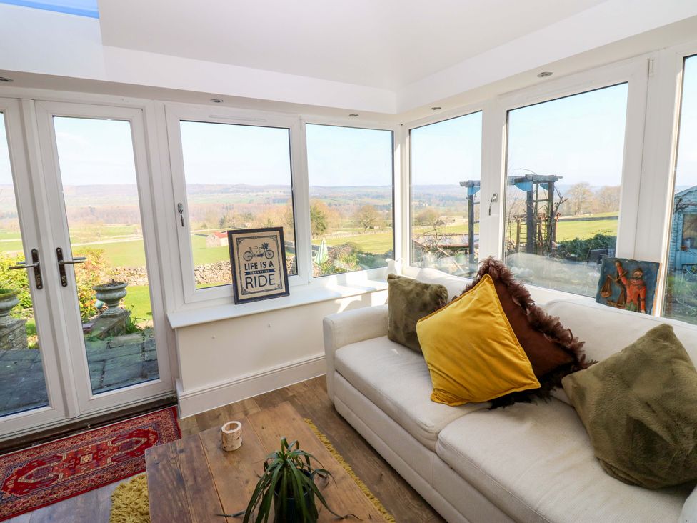 A conservatory with a sofa and coffee table at Eastend Cottage