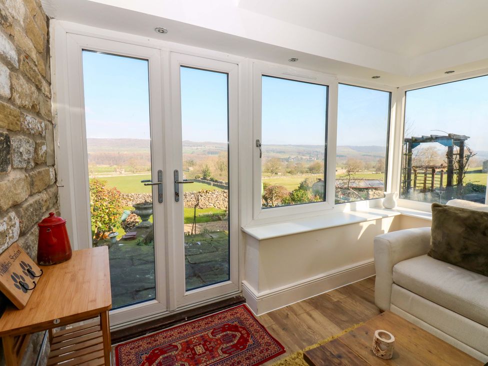 A conservatory with windows and a sofa at Eastend Cottage