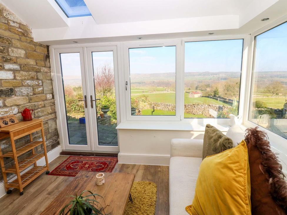 A conservatory with large windows and a coffee table at Eastend Cottage