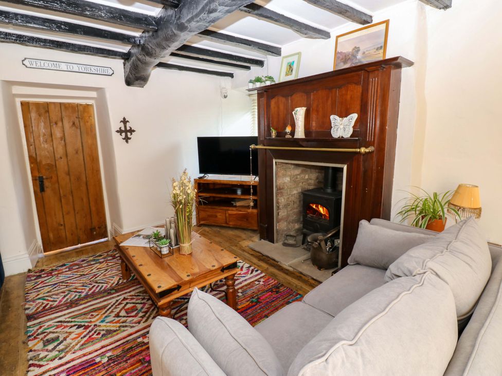 A living room with a sofa, fireplace, and television at Eastend Cottage in 