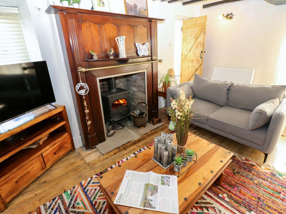A living room with a fireplace and a sofa at Eastend Cottage