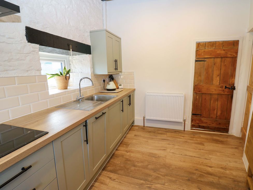 A kitchen with cabinets and a sink at Eastend Cottage