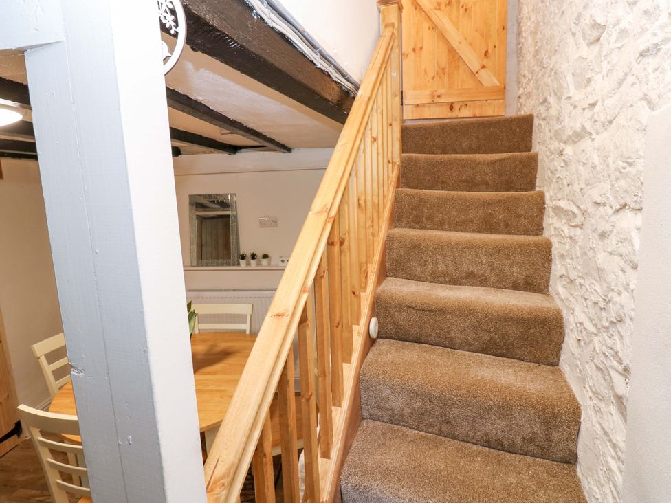 A staircase with a wooden handrail and door at Eastend Cottage