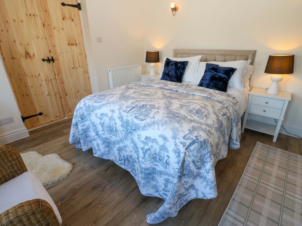 A bedroom with a bed and side table at Eastend Cottage