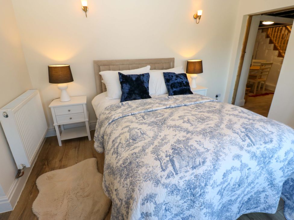 A bedroom with a bed, bedside table and lamps at Eastend Cottage 