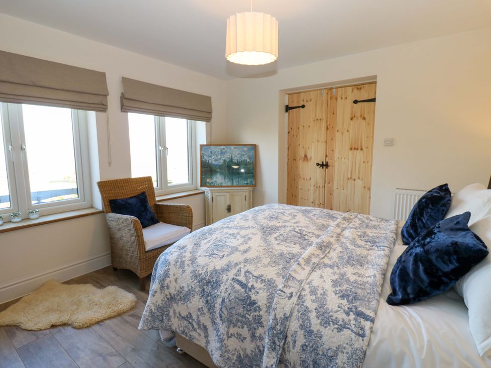 A bedroom with a bed and chair at Eastend Cottage