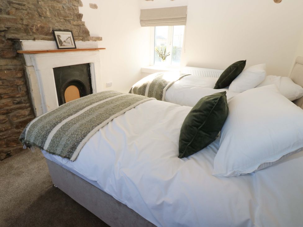 A bedroom with two beds and a fireplace at Eastend Cottage in 