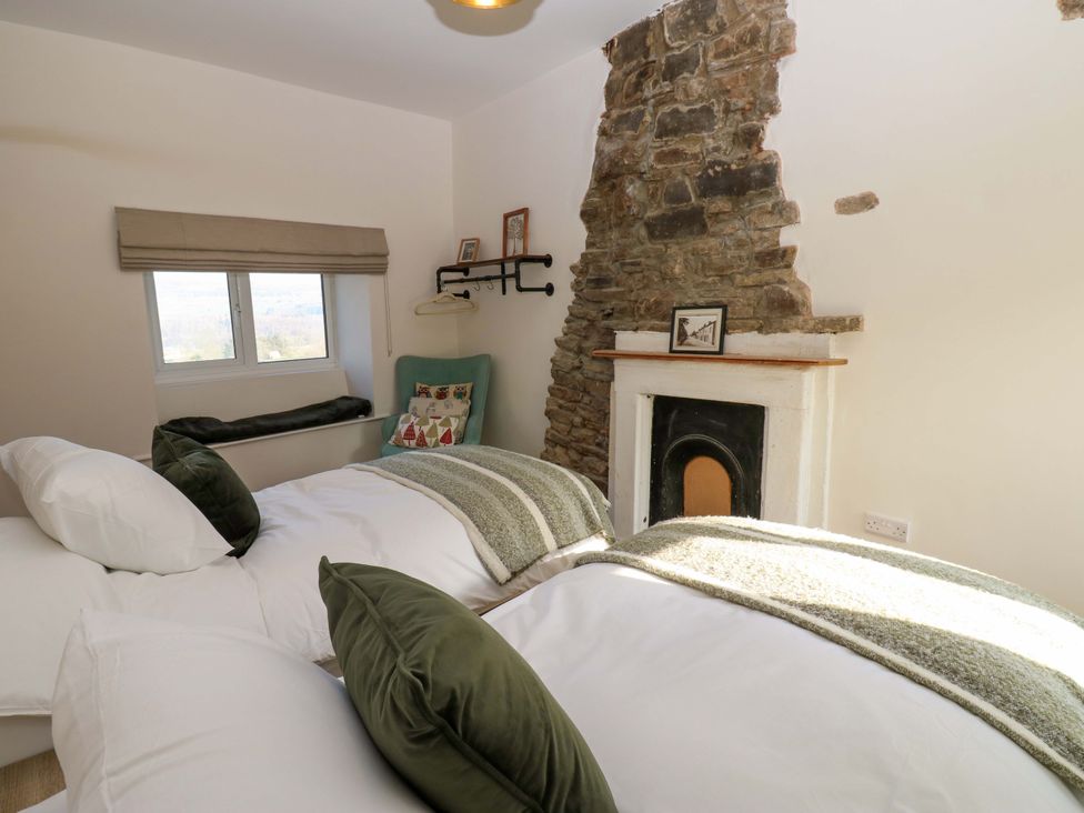 A bedroom with two beds and a stone wall at Eastend Cottage