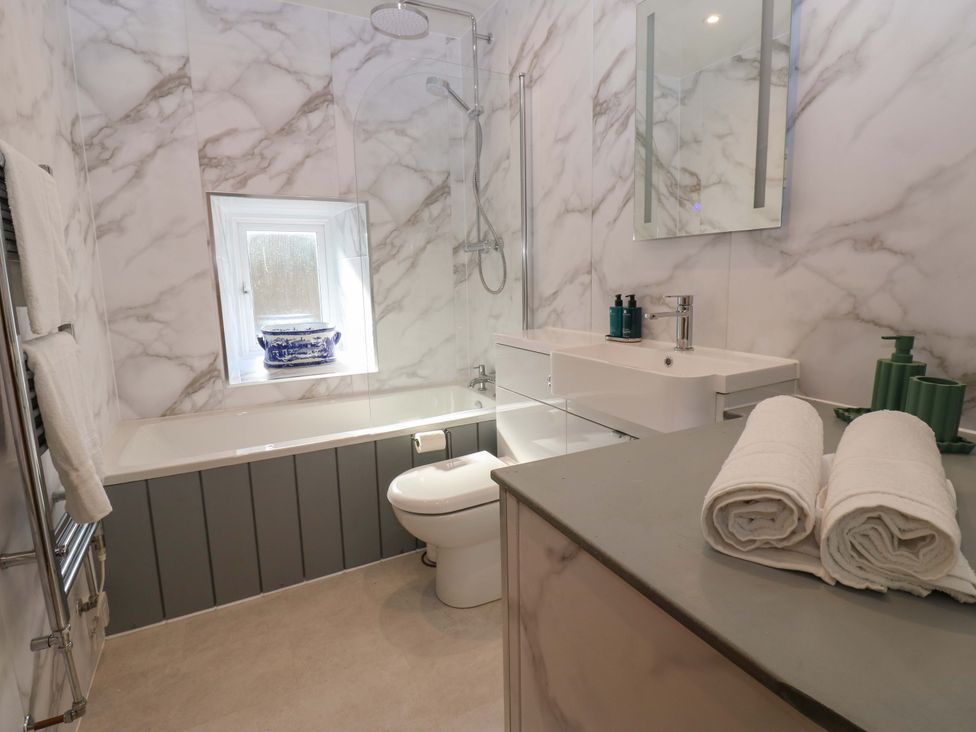 A bathroom with a bathtub, sink, and shower at Eastend Cottage