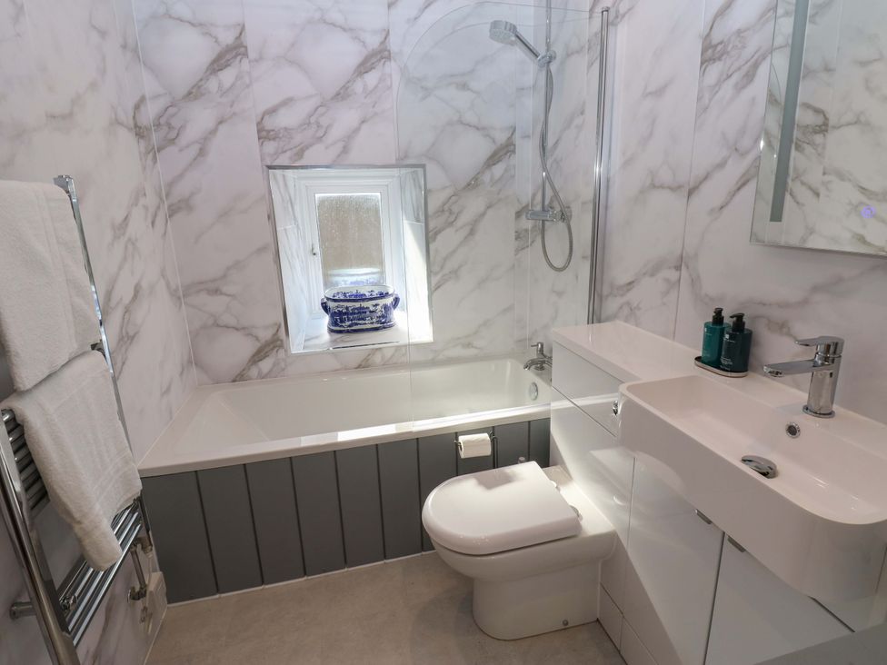 A bathroom with a bathtub, shower, toilet, and sink at Eastend Cottage in 