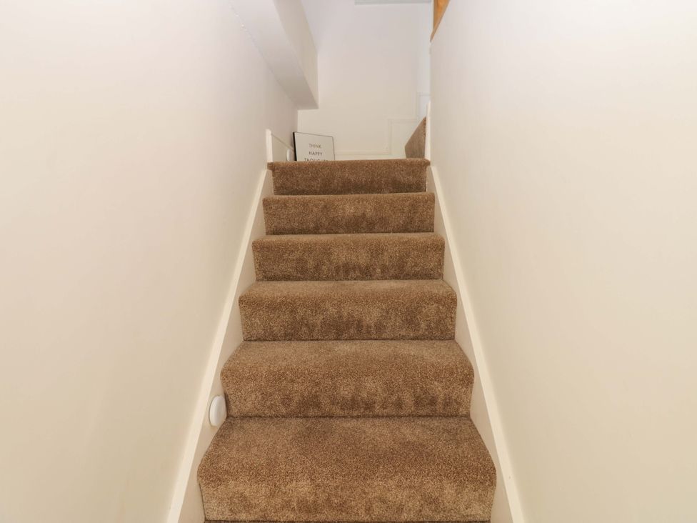 A staircase with carpet leading upward at Eastend Cottage