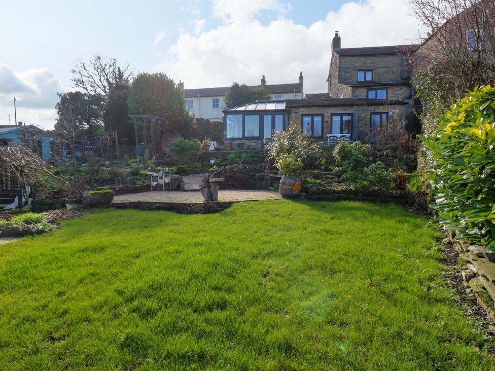 A garden with grass and patio at Eastend Cottage