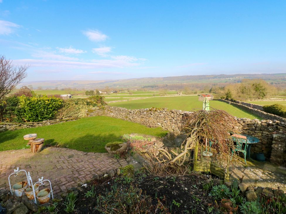 A garden with stone walls and a table at Eastend Cottage