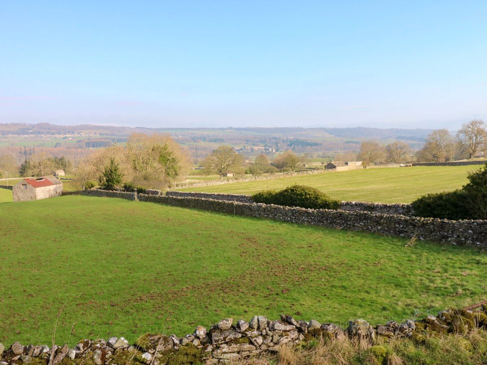 A view of a field with a shed and stone walls at Eastend Cottage