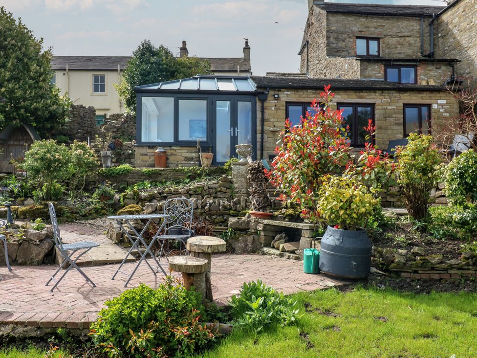 A garden with a conservatory and furniture at Eastend Cottage in West Witton