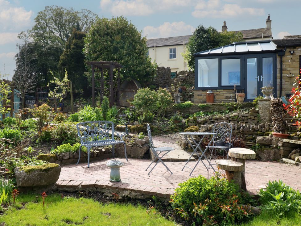 A garden with seating area and plants at Eastend Cottage in West Witton