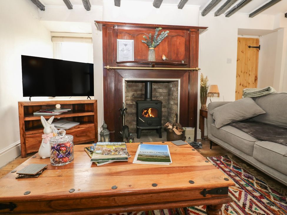 A living room with a fireplace and television at Eastend Cottage in West Witton