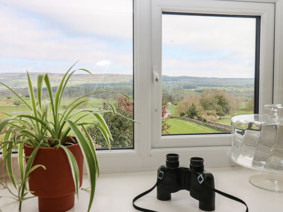 A window with a view, a plant, and binoculars at Eastend Cottage in West Witton