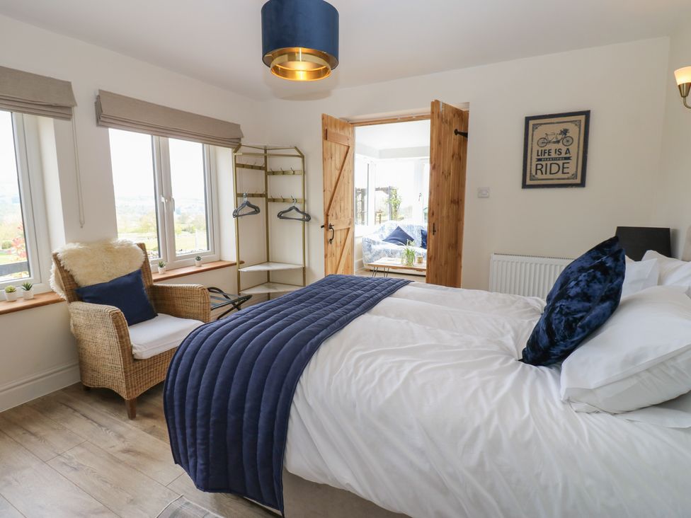 A bedroom with a bed and chair at Eastend Cottage in West Witton
