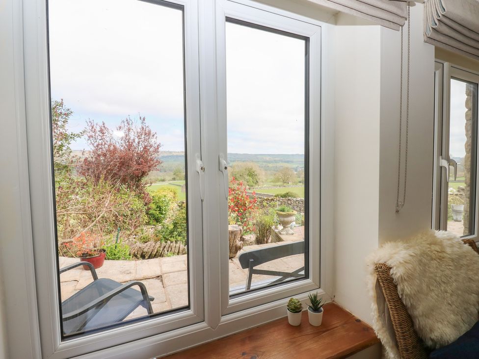A window view of a garden with chairs and plants at Eastend Cottage West Witton