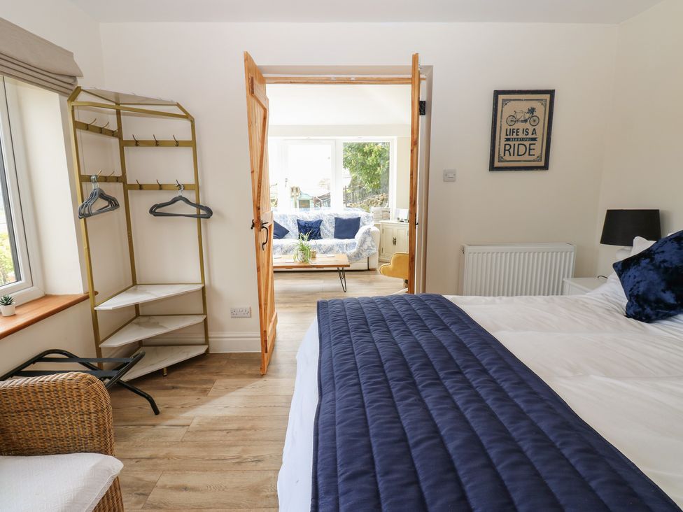 A bedroom with a bed and door leading to a living space at Eastend Cottage in West Witton
