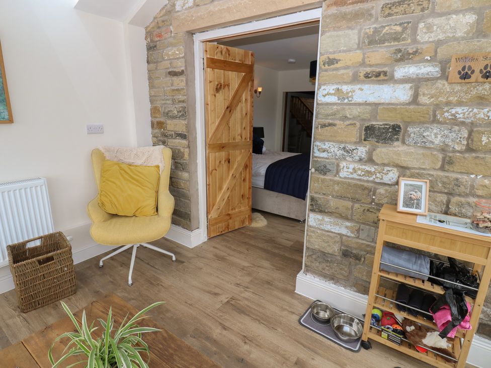A living room with an armchair and a door leading to another room at Eastend Cottage in West Witton