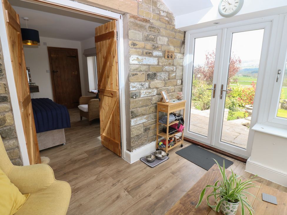 An entrance hall with wooden doors and a window at Eastend Cottage in West Witton