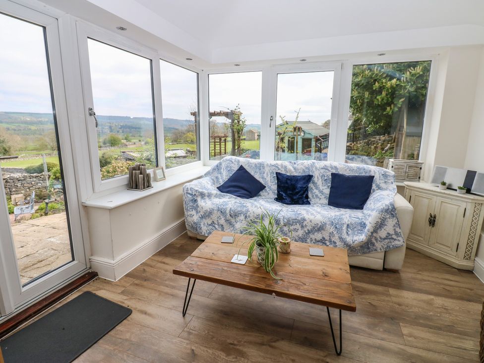 A conservatory with a sofa and coffee table at Eastend Cottage in West Witton