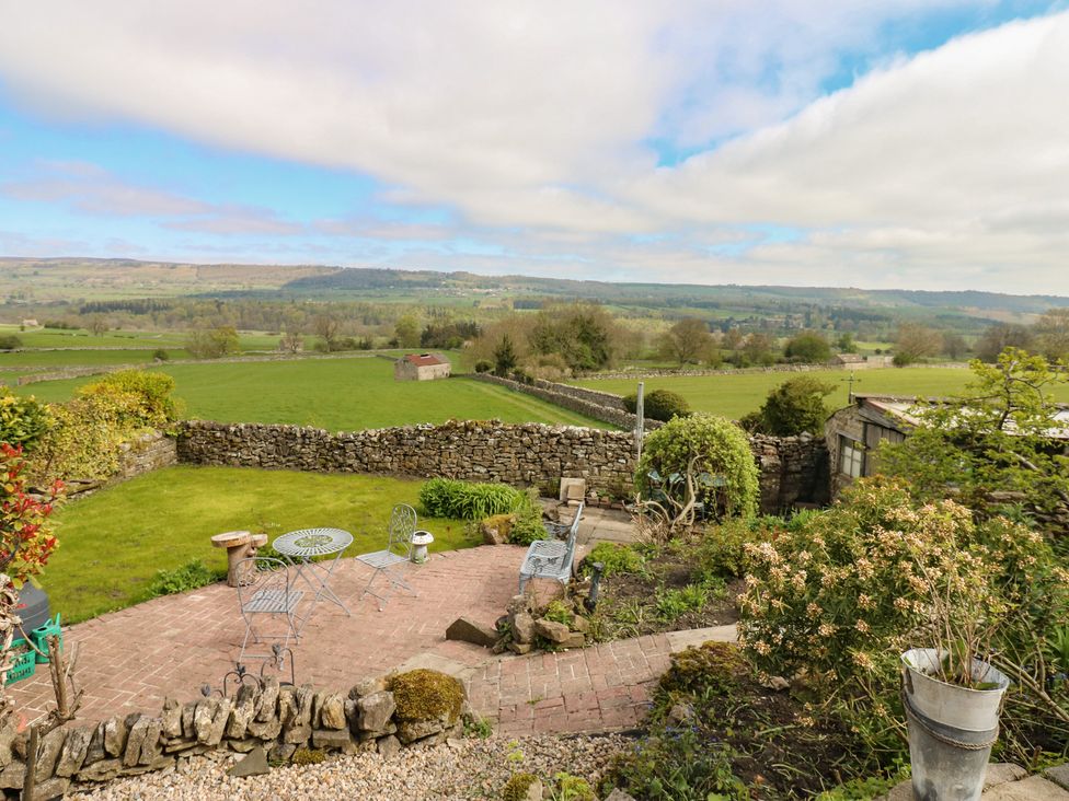 A garden with a patio, table, and chairs at Eastend Cottage in West Witton