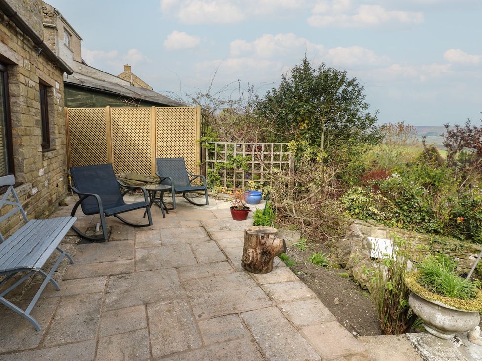 A patio with chairs and plant pots at Eastend Cottage in West Witton