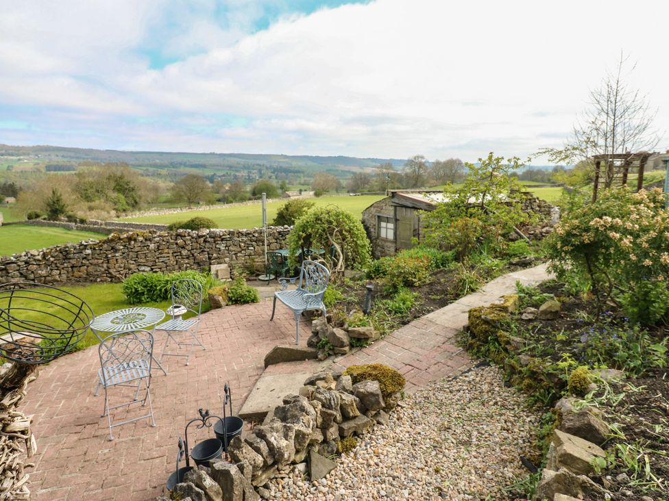 A garden with seating area and plants at Eastend Cottage in West Witton