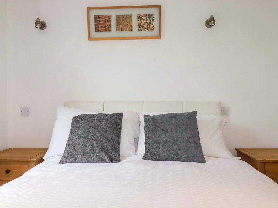 A bed with pillows and nightstands at Sea Thrift near Indian Queens