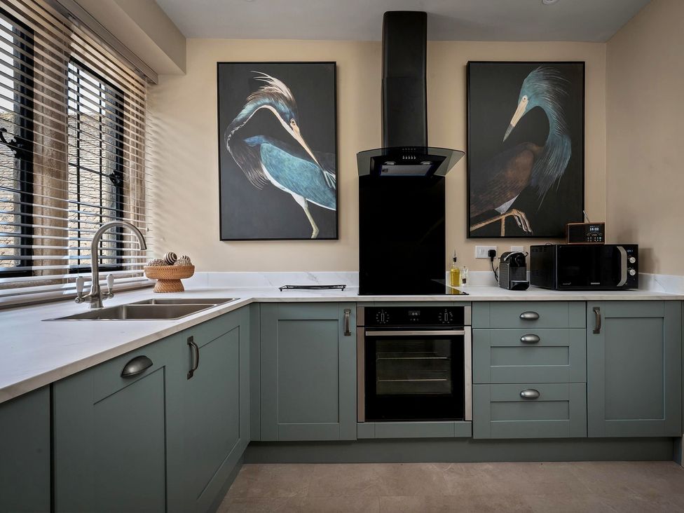A kitchen with cabinets, oven, microwave, and sink at Whistler Rooms