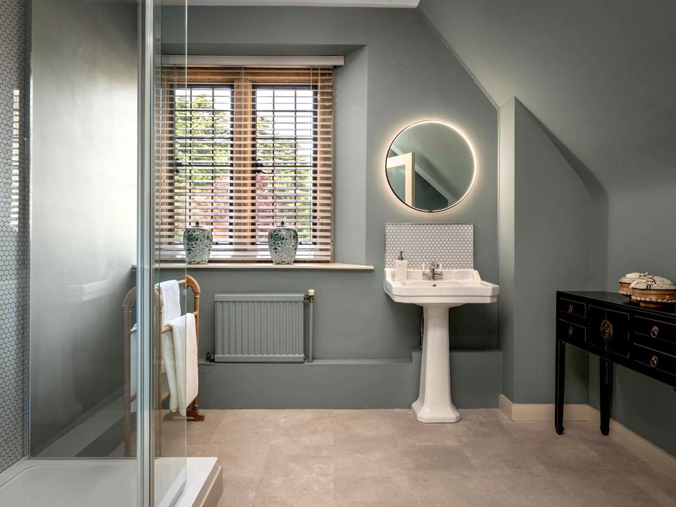 A bathroom with a shower, sink, and window at Whistler Rooms