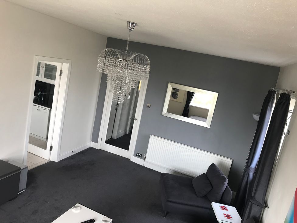 A living room with a chandelier and a mirror in Sea Views No 8 Plas Darien Trearddur Bay