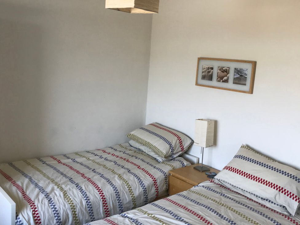 A bedroom with two beds and a nightstand at Sea Views No 8 Plas Darien in Trearddur Bay