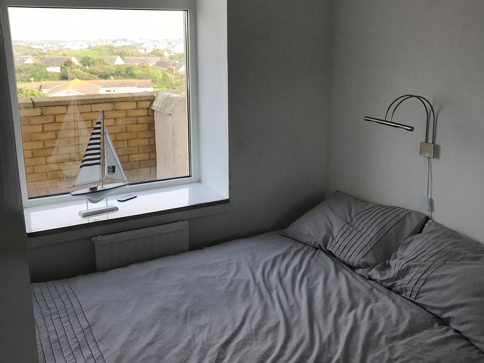A bedroom with a bed and a model sailboat on the windowsill at Sea Views No 8 Plas Darien Trearddur Bay