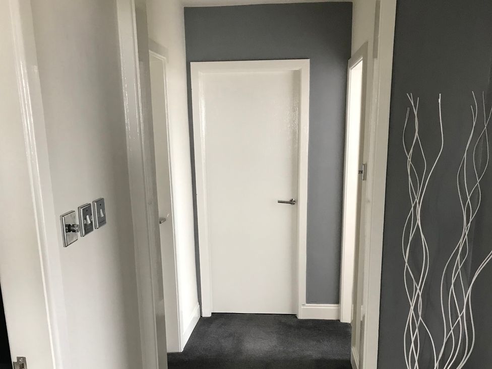 A hallway with white doors and light switches at Sea Views No 8 Plas Darien Trearddur Bay