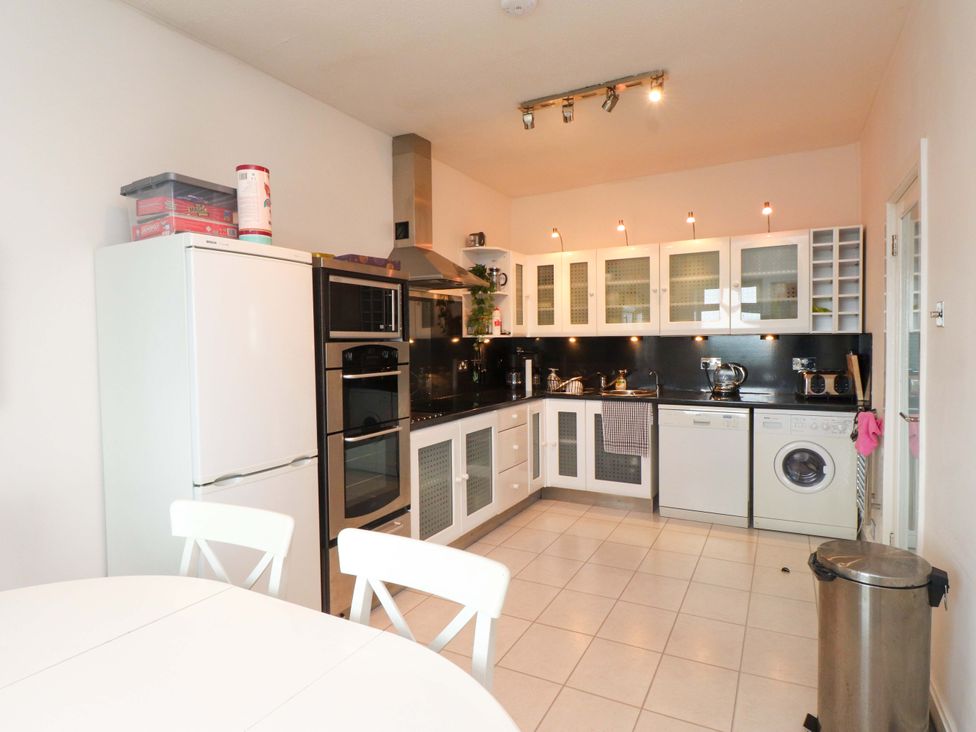 A kitchen with appliances and a dining table at Sea Views No 8 Plas Darien in Trearddur Bay