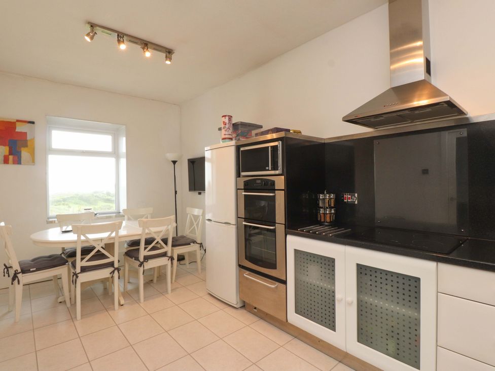 A kitchen with dining table and appliances at Sea Views No 8 Plas Darien in Trearddur Bay